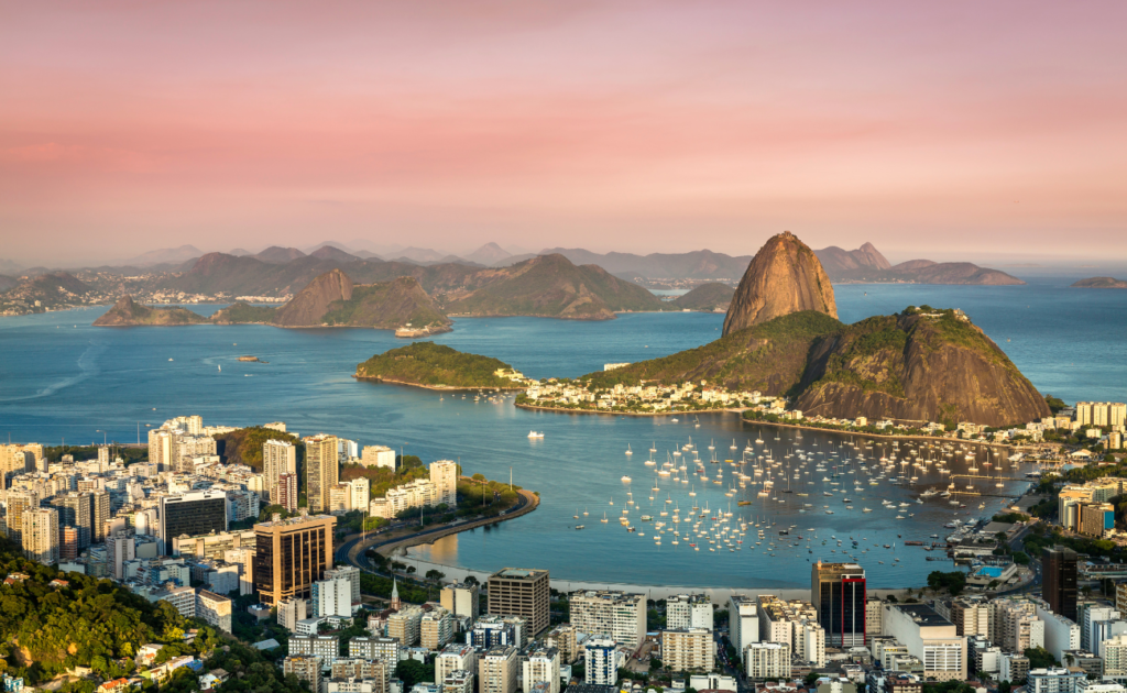 Praia de Copacabana, um dos melhores destinos da América do Sul, Rio de Janeiro, com vista do Pão de Açúcar e pessoas aproveitando o sol e o mar.