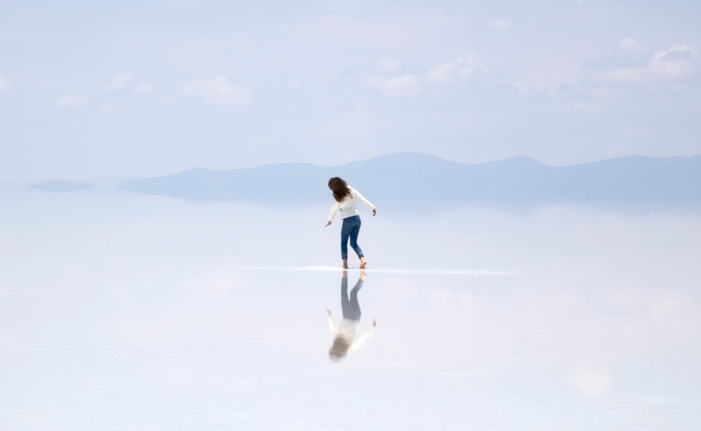 Salar de Uyuni na Bolívia, o maior deserto de sal do mundo, com céu azul refletido na superfície lisa como um espelho.